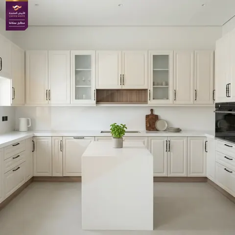 جزيرة مطبخ بيضاء بتصميم شاكر كلاسيكي محفور مع سطح حجري وأدراج تخزين واسعة.