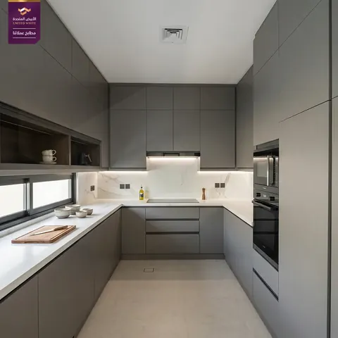 مطبخ رمادي داكن مطفأ بتصميم متصل يدمج مسطح الحث الحراري وأبراج الأجهزة الكهربائية.