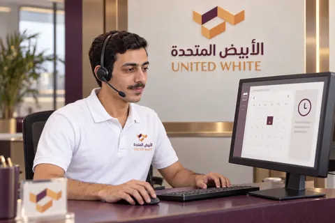 منسق خدمة العملاء بقميص الشركة وسماعة الرأس ينظم مواعيد الزيارات وجداول الصيانة عبر الشاشة، مع شعار الشركة بالخلفية.